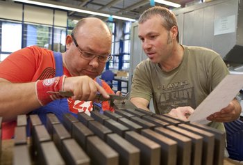 Caritas/Diakonie Zwei Männer arbeiten in der Produktionshalle einer Einrichtung, in der Menschen mit Behinderung gefördert werden