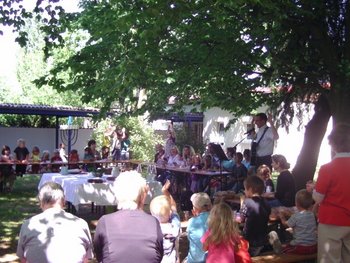 Ökumenische Kinderkirche Billigheim-Ingenheim Kinder sitzen mit ihren Eltern in einem Garten und feiern gemeinsam Gottesdienst